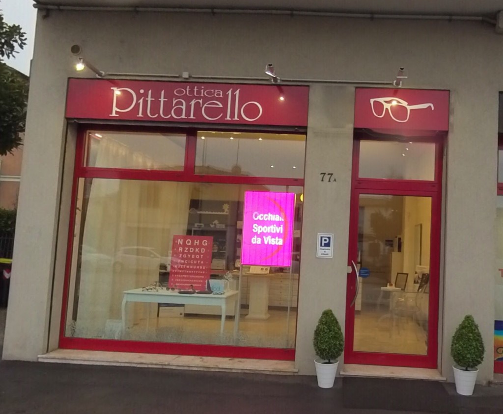 Vetrina di Ottica Pittarello in Via dei Colli a Padova: insegna rossa, porta a vetro e display di occhiali